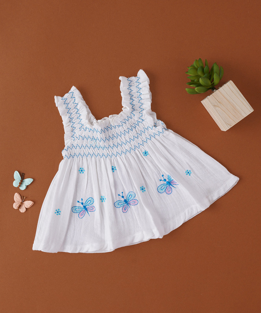 🦋 White Muslin Baby Frock with Blue Butterfly Embroidery & Smocked Ruffle Straps